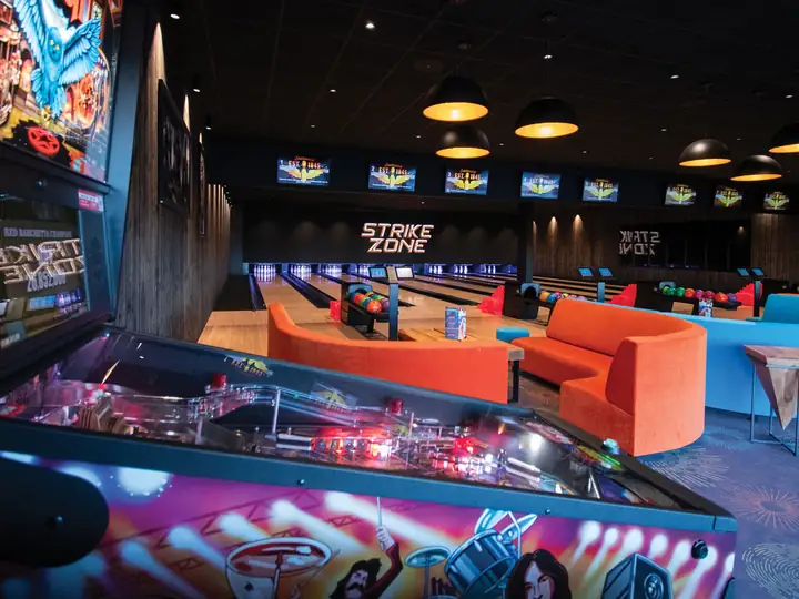 Salle de bowling Strike Zone avec ses pistes, ses canapés et ses bornes de jeu